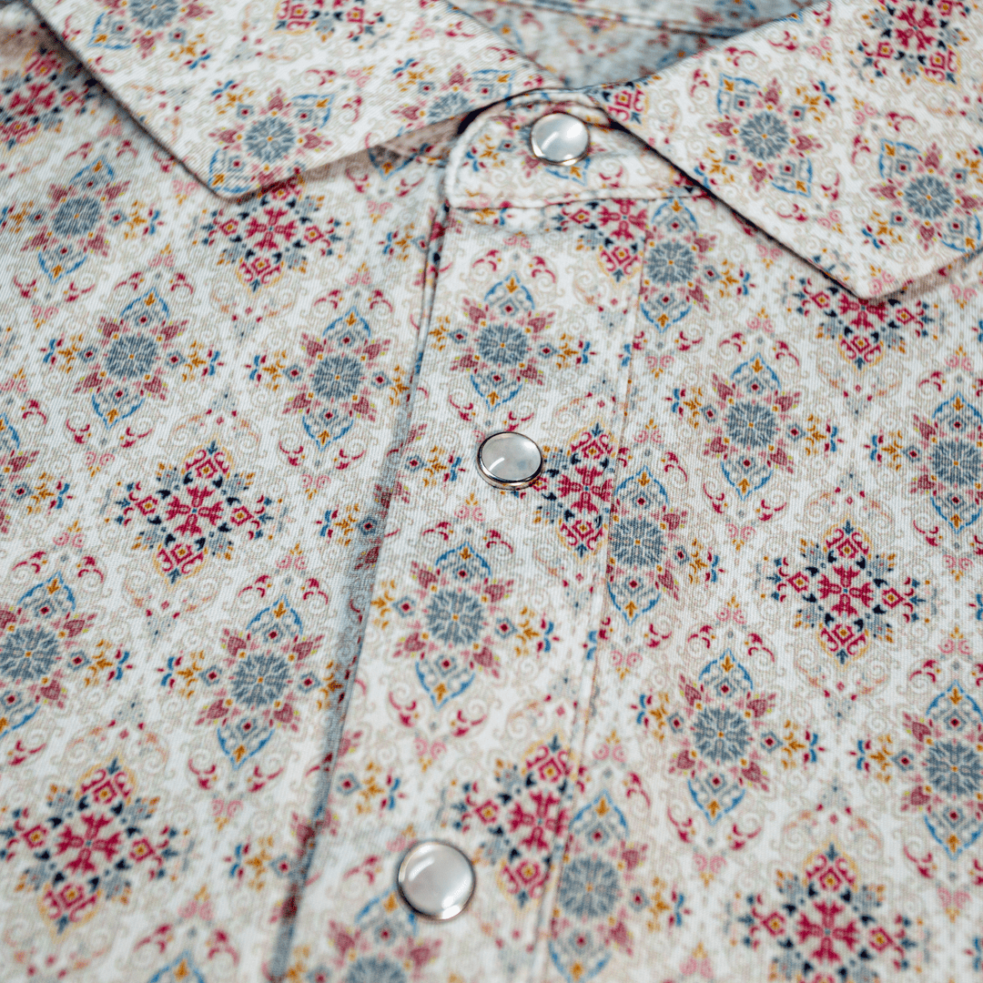 Close-up of The Classic Pearl Snap Polo by Iron Oak Apparel, featuring an intricate floral western pattern with vibrant colors and signature pearl snap buttons. This stylish shirt blends modern design with Texan authenticity, ideal for any occasion.