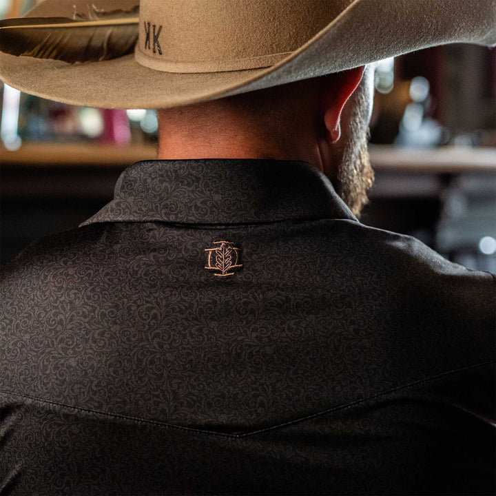 Back view of The Folsom Western Yoke Pearl Snap Polo by Iron Oak Apparel, showcasing the subtle black paisley Western pattern and the embroidered Iron Oak logo.