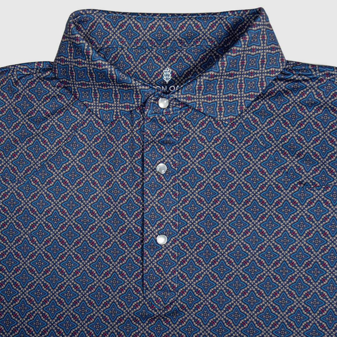 Flat lay of The Granger Western Yoke Pearl Snap Polo by Iron Oak Apparel, featuring a classic blue Western pattern with signature pearl snap buttons and a rigid collar.