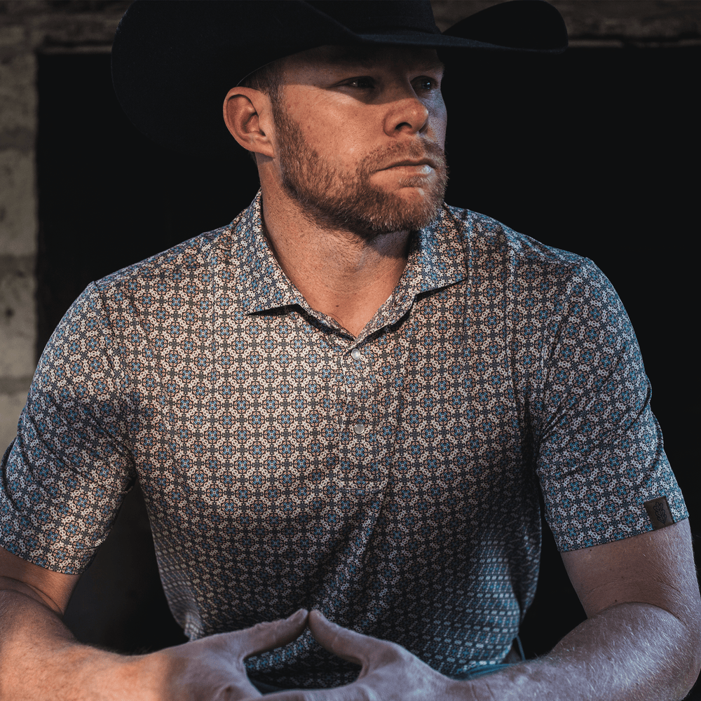 Man wearing The Jaded Pearl Snap Polo by Iron Oak Apparel, exuding confidence and style in a dimly lit setting.