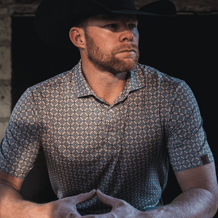 Man wearing The Jaded Pearl Snap Polo by Iron Oak Apparel, exuding confidence and style in a dimly lit setting.