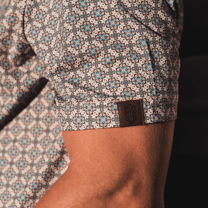 Close-up of the sleeve of The Jaded Pearl Snap Polo by Iron Oak Apparel, featuring the geometric western pattern and Iron Oak logo tag.