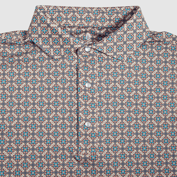 Close-up of The Jaded Pearl Snap Polo by Iron Oak Apparel, showcasing its intricate blue and orange geometric western pattern.