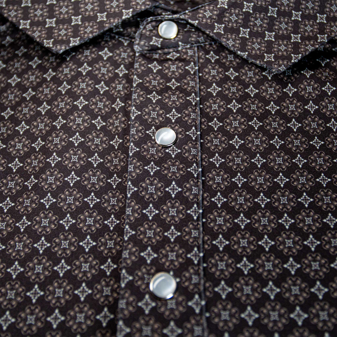 Close-up of The Bandit Pearl Snap Polo by Iron Oak Apparel, featuring a detailed western pattern in shades of brown and black, along with signature pearl snap buttons. This stylish shirt combines modern design with Texan authenticity, perfect for elevating any casual outfit.