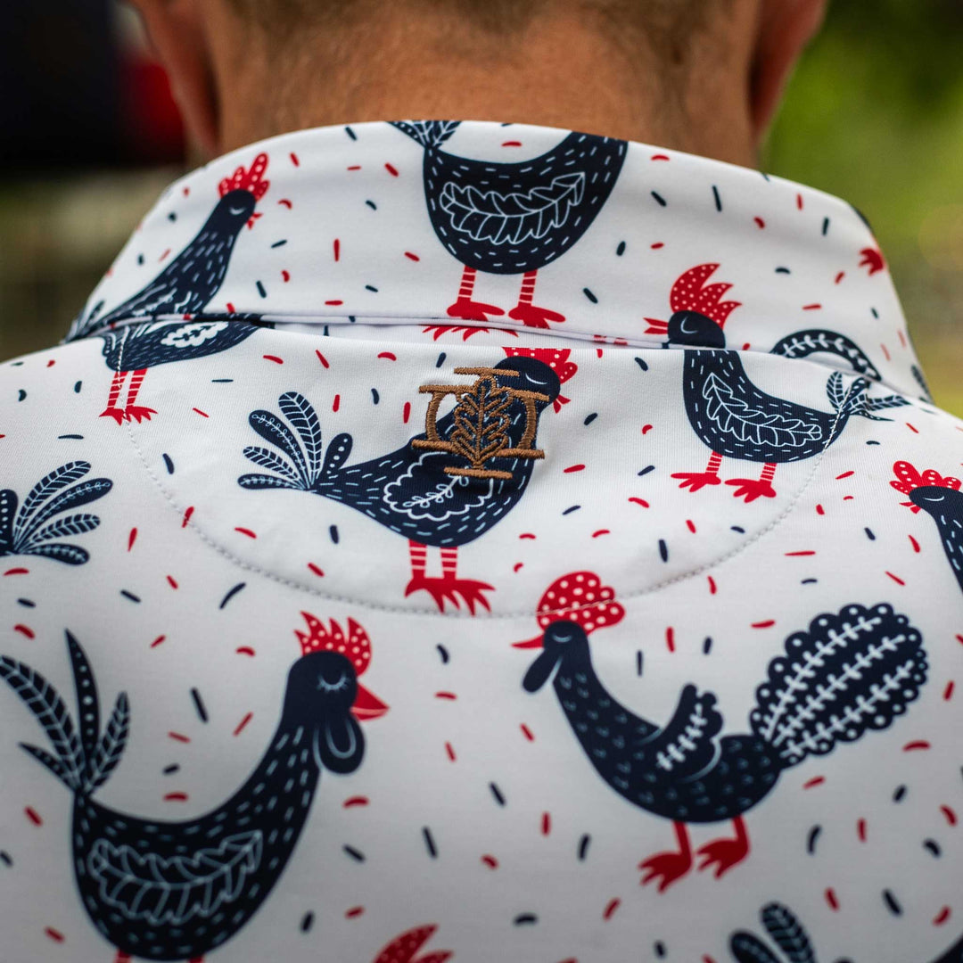 Back view of The Cock-a-doo Pearl Snap Polo by Iron Oak Apparel, highlighting the whimsical pattern of navy blue roosters with red accents on a white background and the embroidered logo. This fun and stylish shirt is perfect for adding a touch of personality to your wardrobe.