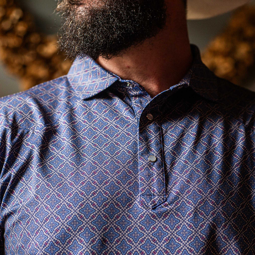 Close-up of The Granger Western Yoke Pearl Snap Polo by Iron Oak Apparel, highlighting the intricate blue Western pattern and the signature pearl snap buttons.