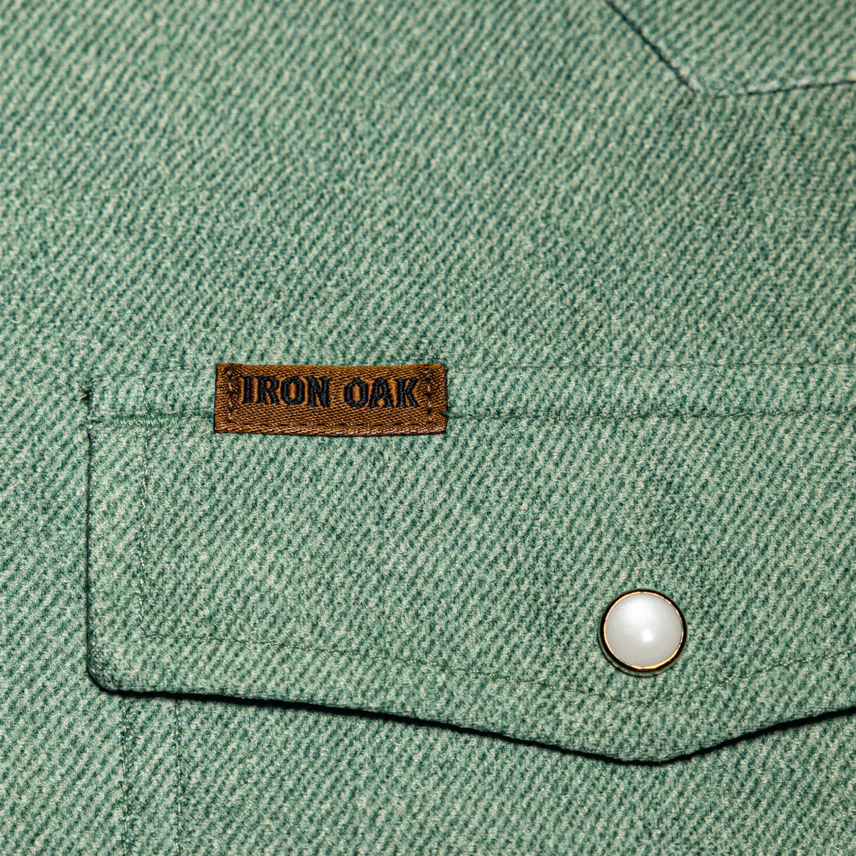 Close-up of the Monte's sage green jacquard fabric texture and pearl-snap pocket