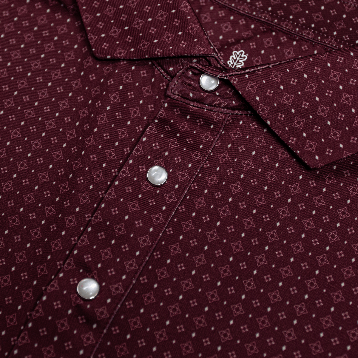 Close-up of The Bennett Pearl Snap Polo by Iron Oak Apparel, showcasing a detailed maroon western pattern and signature pearl snap buttons. This stylish shirt combines modern design with Texan authenticity, perfect for any casual or dressy occasion.