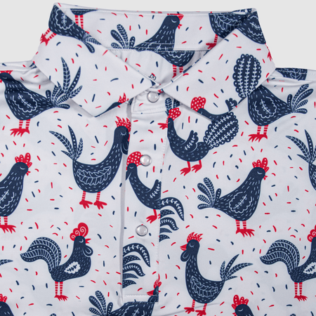 Flat lay of The Cock-a-doo Pearl Snap Polo by Iron Oak Apparel, featuring a whimsical pattern of navy blue roosters with red accents on a white background. This fun and stylish shirt is perfect for adding a touch of personality to your wardrobe.