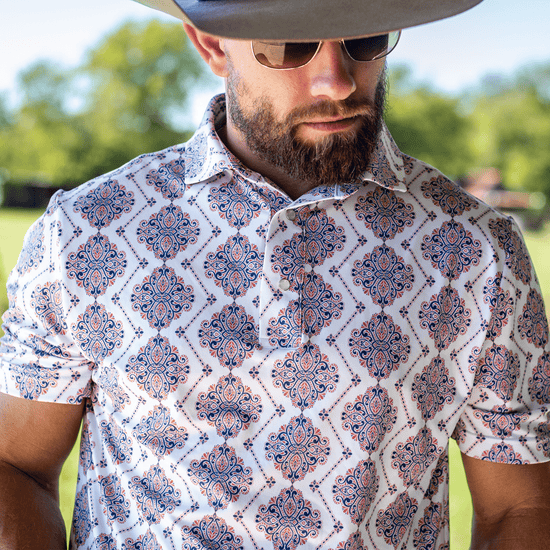 Man wearing The Hold 'Em Pearl Snap Polo by Iron Oak Apparel, showcasing the vibrant pattern. He stands outdoors, exuding confidence and style.