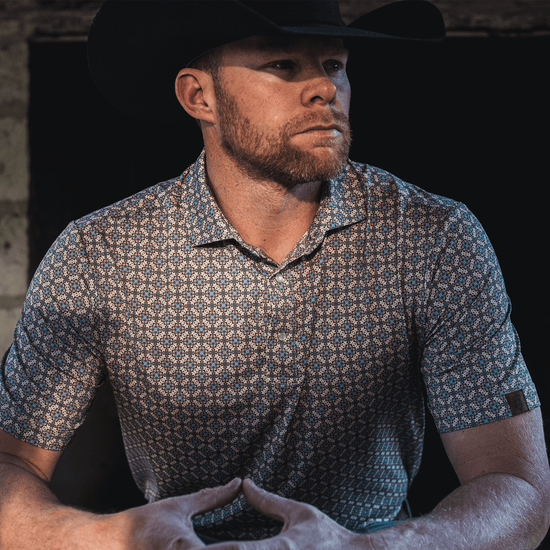 Man wearing The Jaded Pearl Snap Polo by Iron Oak Apparel, exuding confidence and style in a dimly lit setting.
