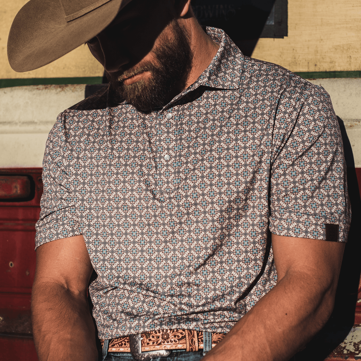 Man wearing The Jaded Pearl Snap Polo by Iron Oak Apparel, leaning against a vintage truck, showcasing the bold pattern and classic pearl snap buttons.